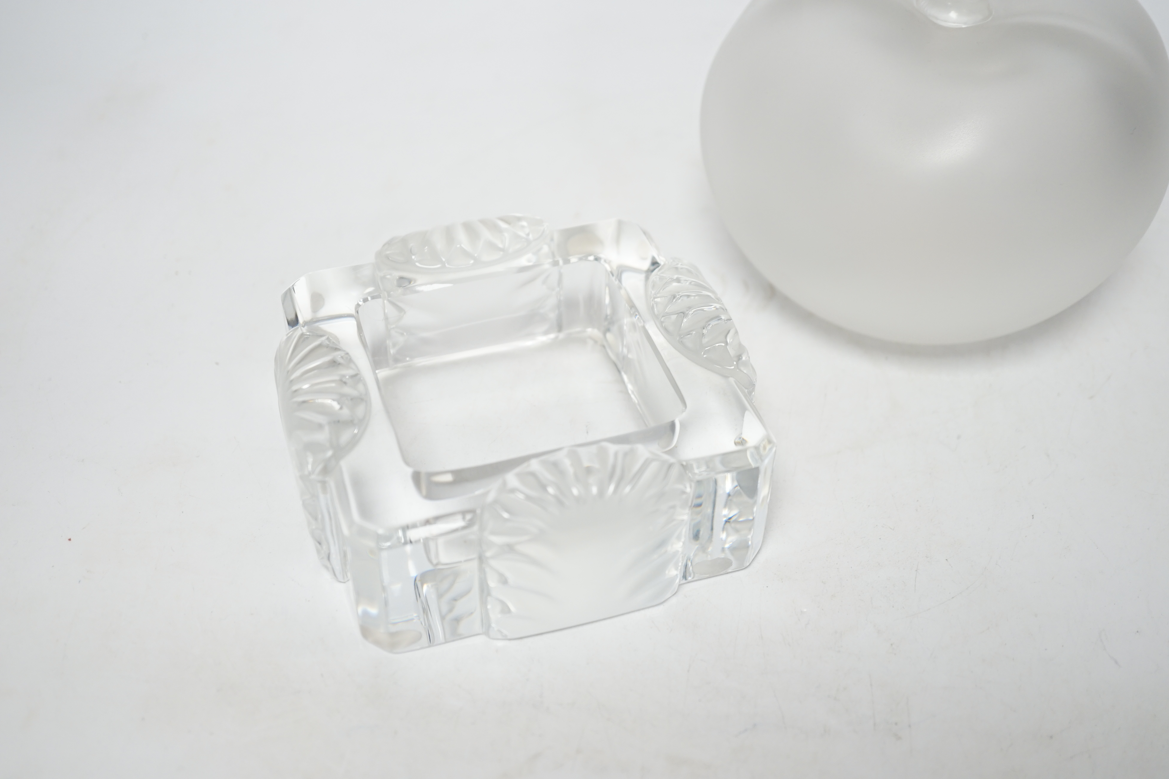 A Lalique apple shaped perfume bottle and leaf stopper together with a square ashtray, both with signed engraving to base, perfume bottle 14cm high